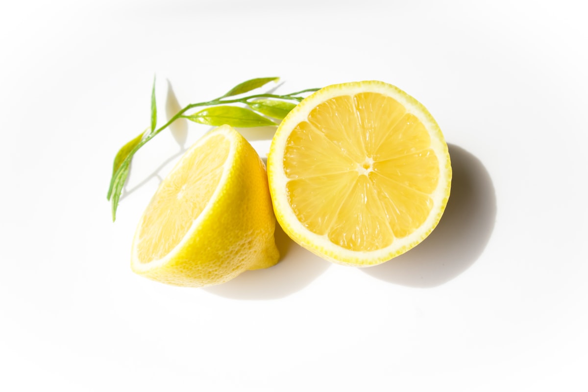 A sliced lemon with green leaves on white